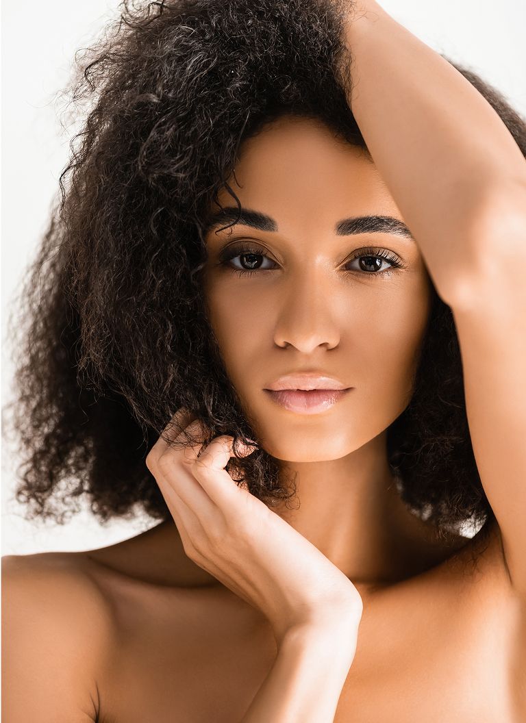 Woman with curly hair posing thoughtfully.