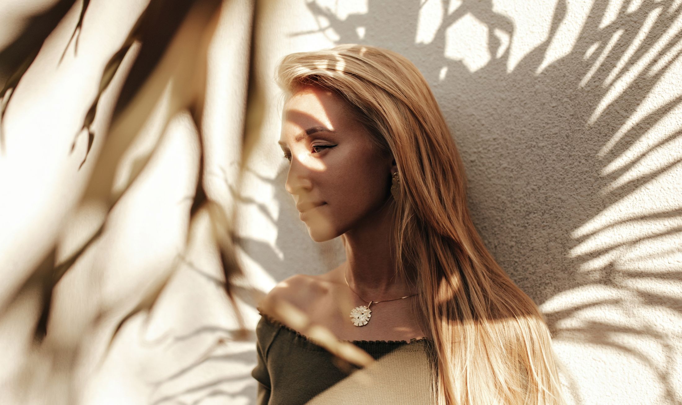 Woman with long hair against shadowed wall.